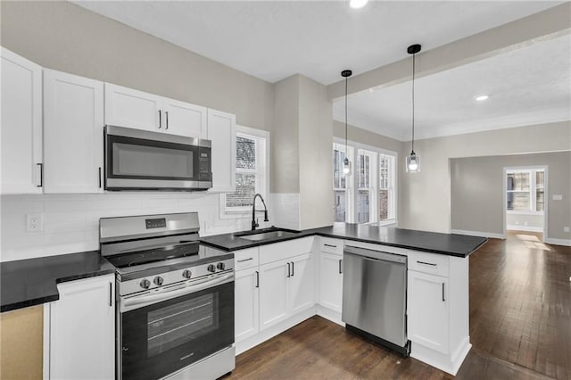 kitchen with kitchen peninsula, stainless steel appliances, sink, white cabinets, and hanging light fixtures