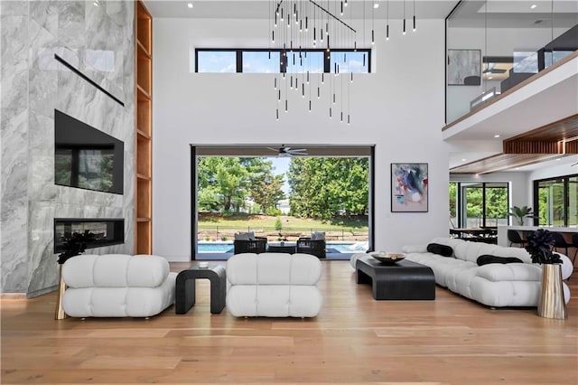 living room featuring a tile fireplace, plenty of natural light, and a high ceiling