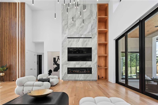 living room with hardwood / wood-style floors, built in features, a fireplace, and a towering ceiling