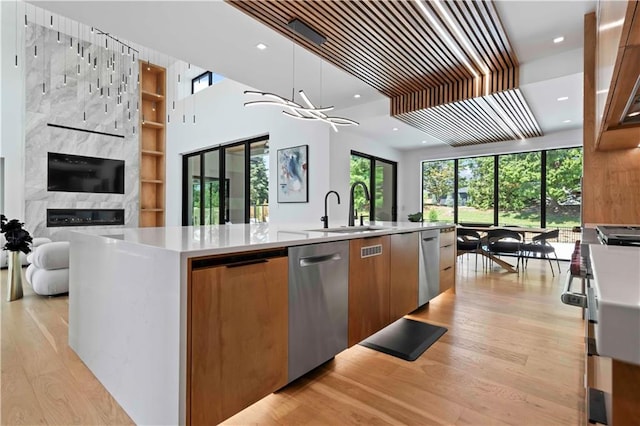 kitchen featuring a large fireplace, sink, pendant lighting, a center island with sink, and dishwasher