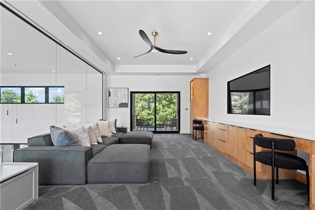 carpeted living room featuring a raised ceiling and ceiling fan