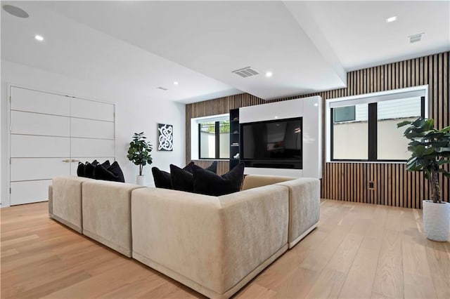 living room with light hardwood / wood-style floors and wooden walls