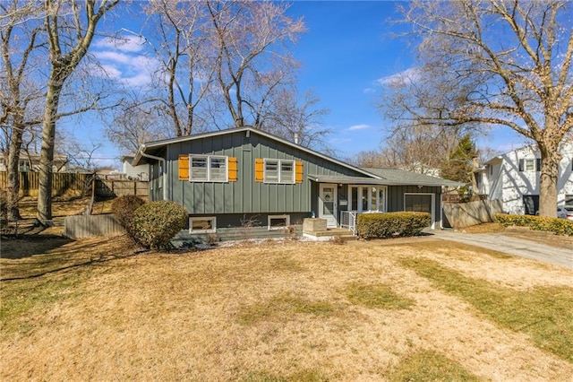 split level home featuring an attached garage, fence, board and batten siding, and driveway