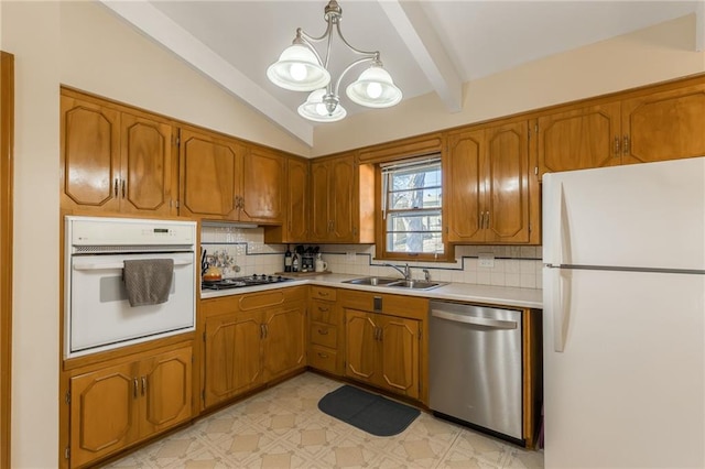 kitchen featuring light floors, light countertops, an inviting chandelier, white appliances, and a sink