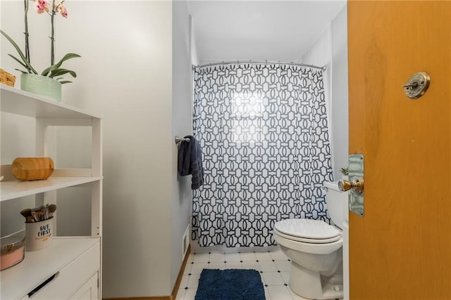 full bathroom featuring a shower with shower curtain, toilet, and tile patterned floors