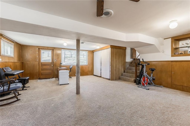 basement with wooden walls, plenty of natural light, stairway, and carpet