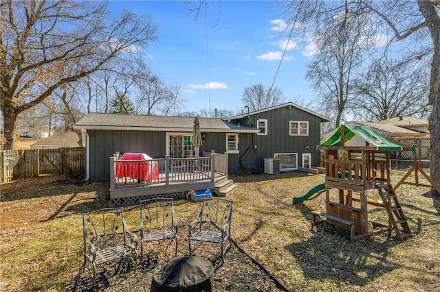 rear view of property featuring board and batten siding, a playground, a wooden deck, cooling unit, and a fenced backyard