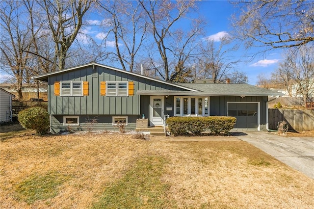 tri-level home featuring board and batten siding, fence, concrete driveway, a front yard, and an attached garage