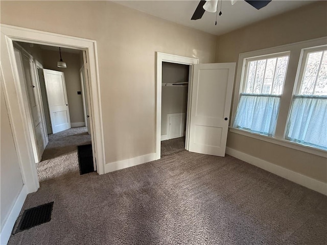 unfurnished bedroom featuring dark colored carpet, ceiling fan, and a closet