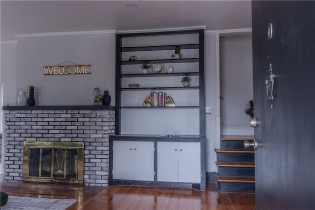 unfurnished living room with built in shelves, dark hardwood / wood-style flooring, and a brick fireplace