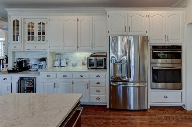 kitchen with white cabinets, decorative backsplash, dark hardwood / wood-style floors, appliances with stainless steel finishes, and beverage cooler