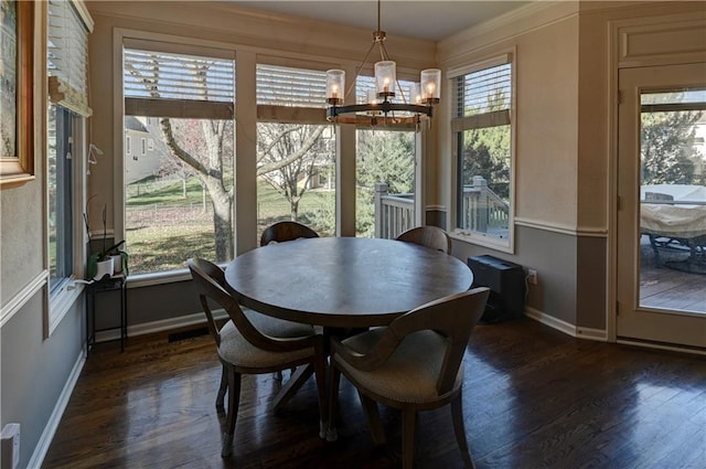 dining area with crown molding, dark wood-type flooring, and a chandelier