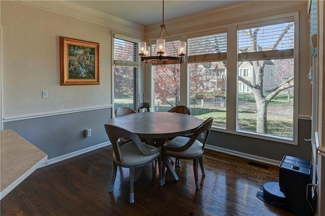 dining room with dark hardwood / wood-style flooring, crown molding, and an inviting chandelier