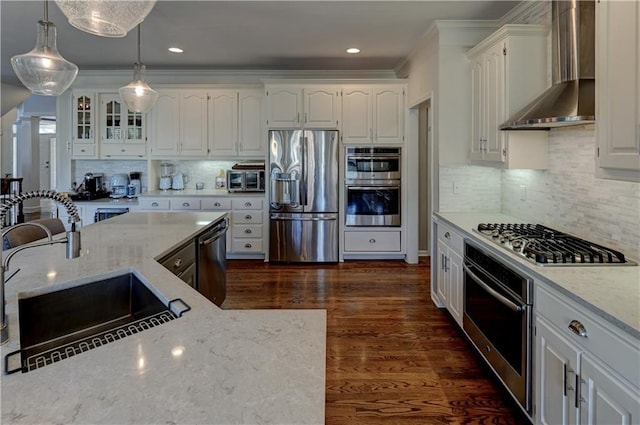 kitchen with white cabinets, appliances with stainless steel finishes, sink, and wall chimney range hood