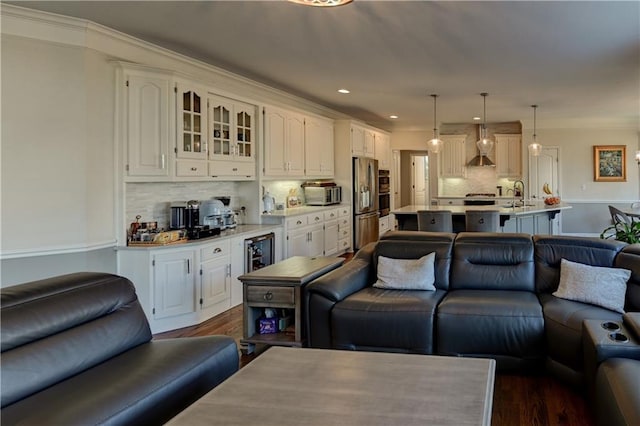 living room featuring crown molding, beverage cooler, dark wood-type flooring, and sink