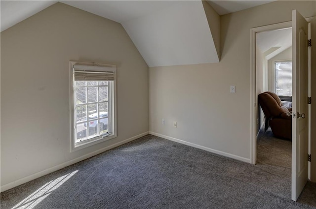 additional living space featuring plenty of natural light, vaulted ceiling, and dark colored carpet