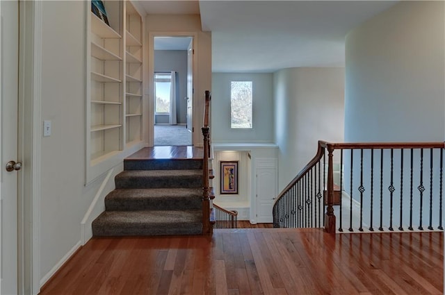 staircase featuring hardwood / wood-style floors and built in features