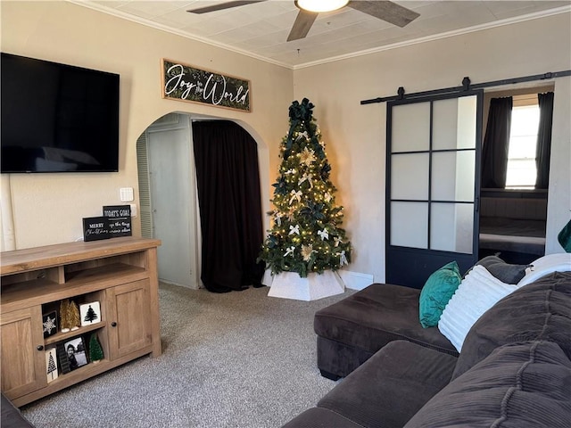 living room featuring a barn door, light carpet, ceiling fan, and ornamental molding