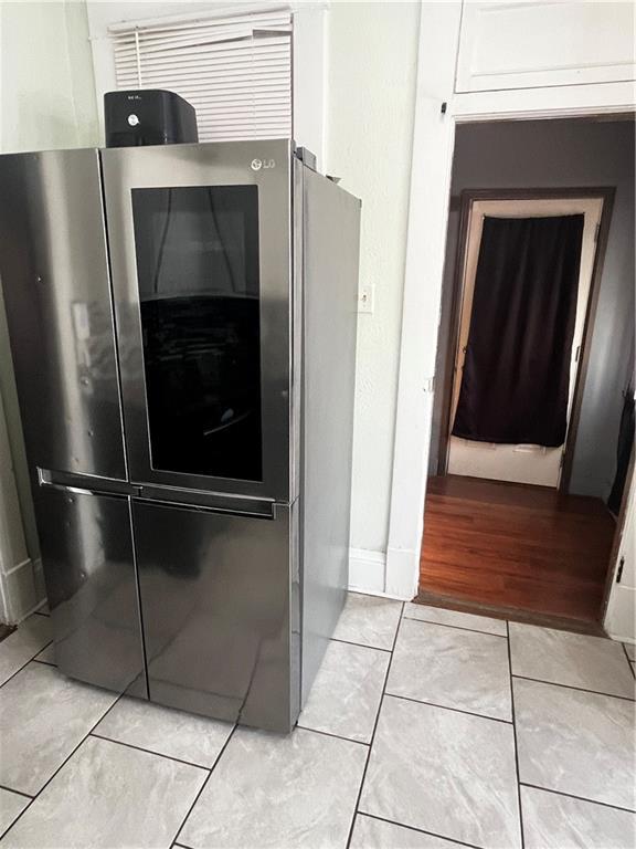 interior details with stainless steel refrigerator, white cabinetry, and light hardwood / wood-style floors