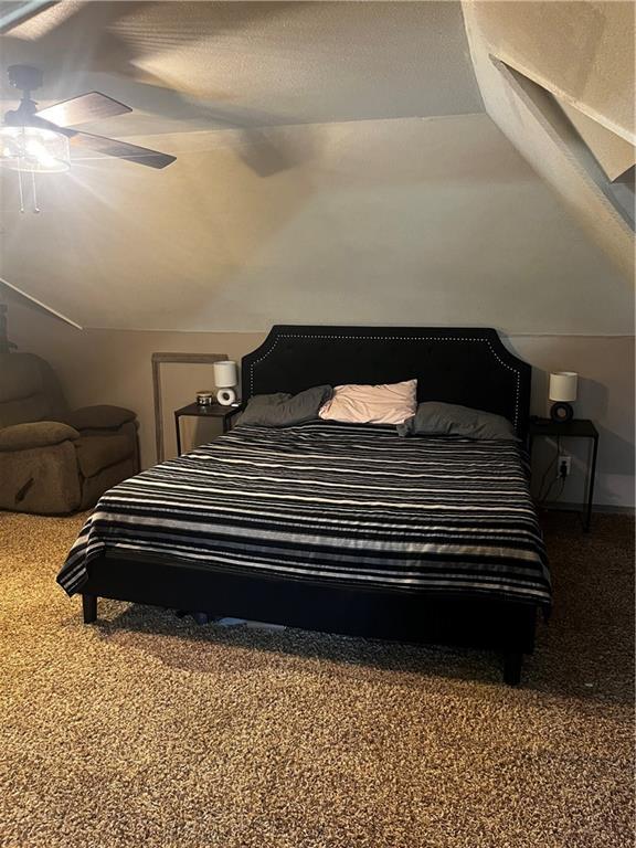 bedroom featuring a textured ceiling, ceiling fan, carpet floors, and lofted ceiling