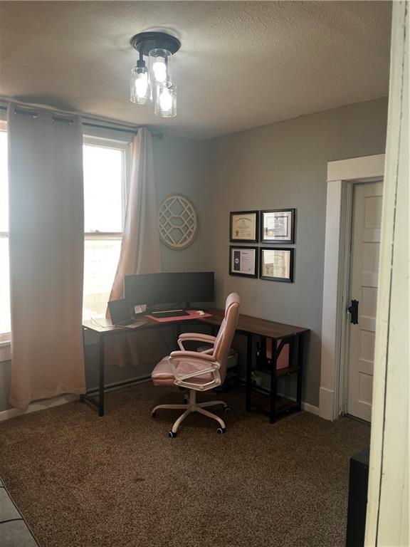 carpeted office space featuring a textured ceiling