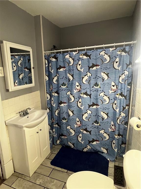 bathroom featuring walk in shower, tile patterned flooring, vanity, and toilet