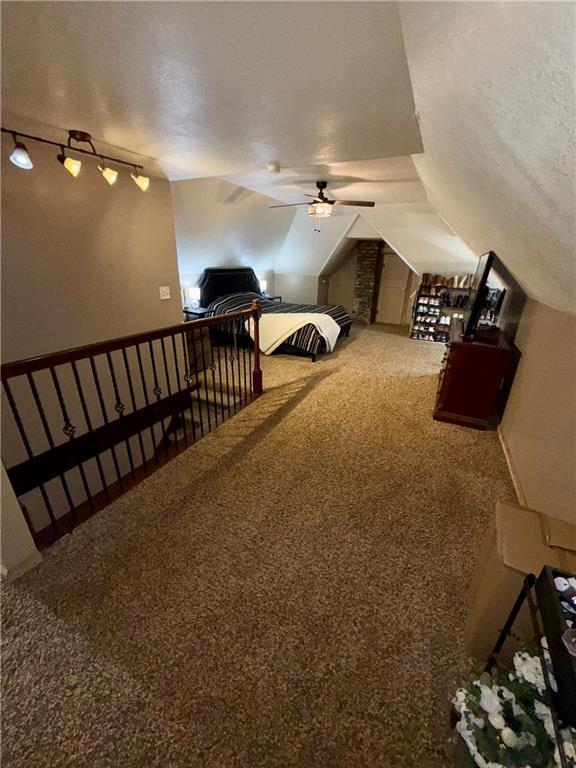 323 W 6th St, Chanute, KS 66720 - carpeted bedroom with ceiling fan, rail lighting, lofted ceiling, and a textured ceiling