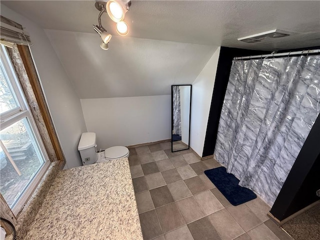 323 W 6th St, Chanute, KS 66720 - full bath with vaulted ceiling, toilet, a textured ceiling, tile patterned flooring, and a shower with shower curtain