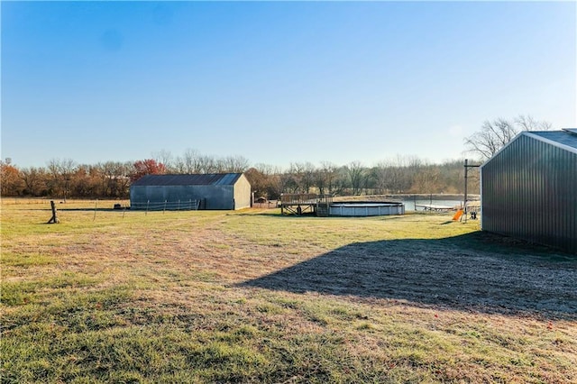 view of yard with a rural view, an outdoor structure, and a swimming pool