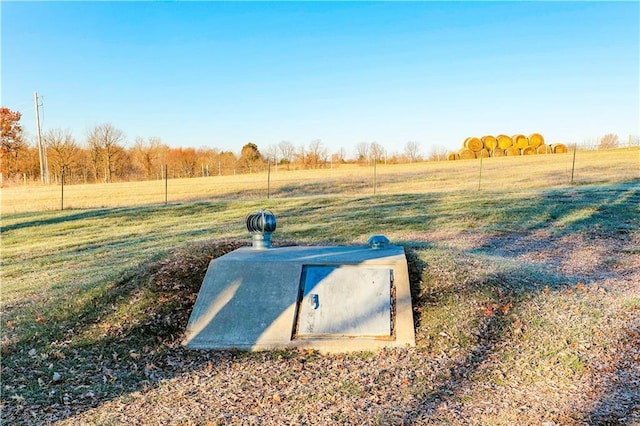 entry to storm shelter featuring a lawn and a rural view