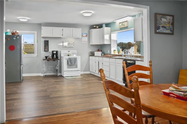 kitchen with stainless steel fridge, electric range, white cabinetry, and a healthy amount of sunlight