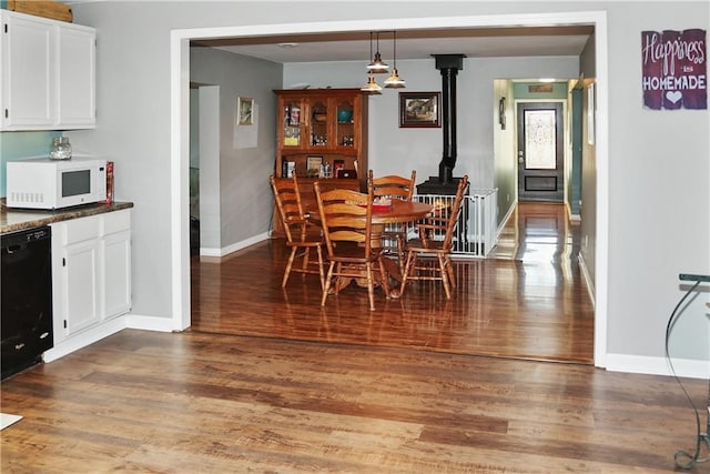 dining area with a wood stove and hardwood / wood-style flooring