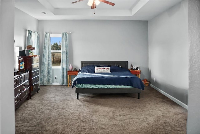 bedroom with carpet flooring, ceiling fan, and a tray ceiling