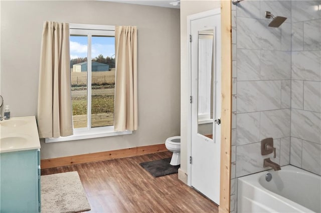 full bathroom featuring hardwood / wood-style flooring, vanity, toilet, and tiled shower / bath