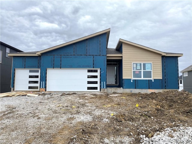 contemporary home with dirt driveway and an attached garage