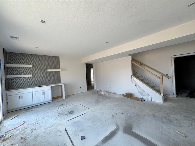 unfurnished living room with stairway and a textured ceiling
