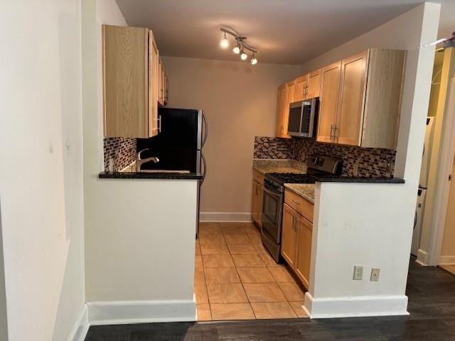 kitchen with white gas stove, light brown cabinets, light tile patterned flooring, and tasteful backsplash