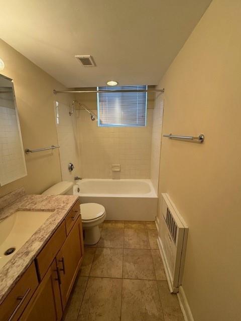 full bathroom with radiator, tile patterned floors, toilet, vanity, and tiled shower / bath