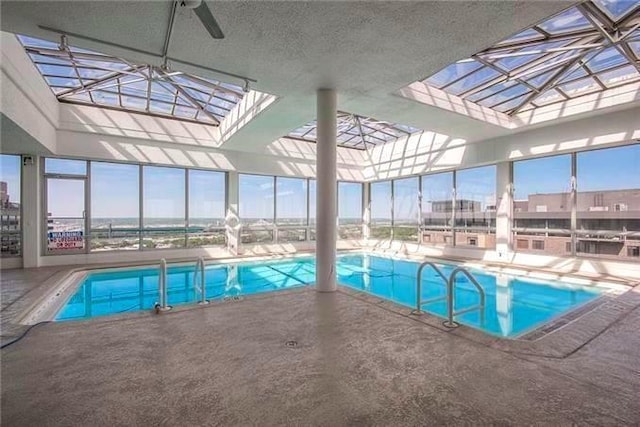 view of pool featuring glass enclosure, ceiling fan, and a patio area