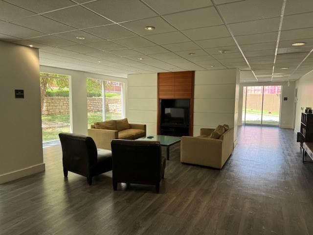 living room with a paneled ceiling and dark hardwood / wood-style flooring