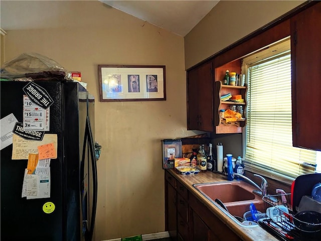 kitchen with vaulted ceiling, black fridge, and sink