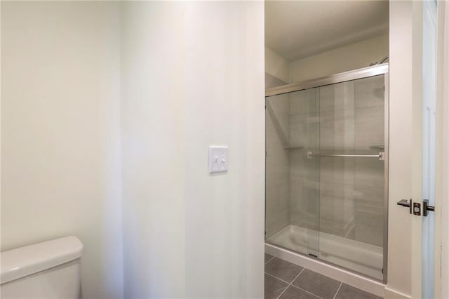 bathroom featuring tile patterned floors, toilet, and an enclosed shower