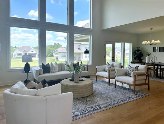 living room featuring french doors, a high ceiling, a notable chandelier, and hardwood / wood-style flooring