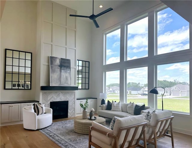 living room featuring plenty of natural light, a tile fireplace, a high ceiling, and light hardwood / wood-style flooring