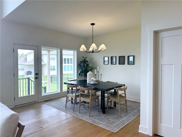 dining space with hardwood / wood-style flooring, a healthy amount of sunlight, and an inviting chandelier