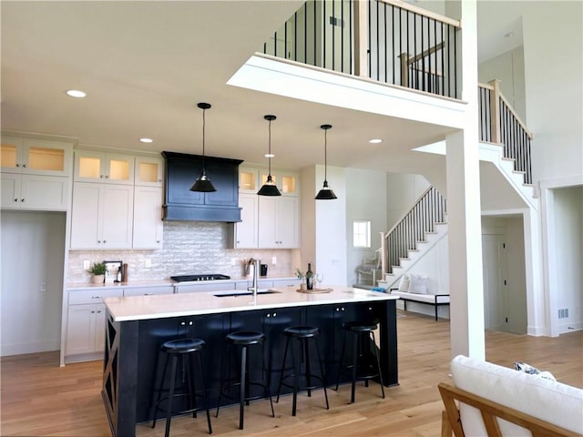 kitchen featuring a kitchen island with sink, light hardwood / wood-style flooring, and hanging light fixtures