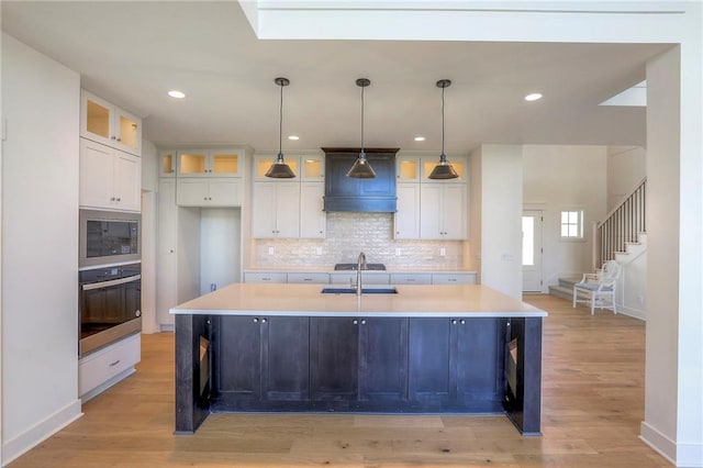 kitchen featuring white cabinetry, a kitchen island with sink, light hardwood / wood-style flooring, and stainless steel appliances