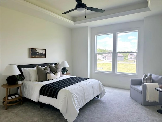 carpeted bedroom featuring ceiling fan and a raised ceiling