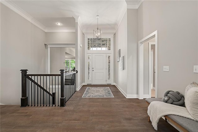 foyer with a high ceiling, dark hardwood / wood-style floors, ornamental molding, and a notable chandelier