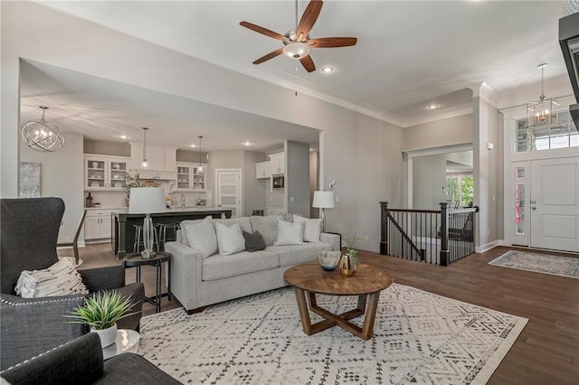 living room with ceiling fan with notable chandelier, hardwood / wood-style flooring, and ornamental molding